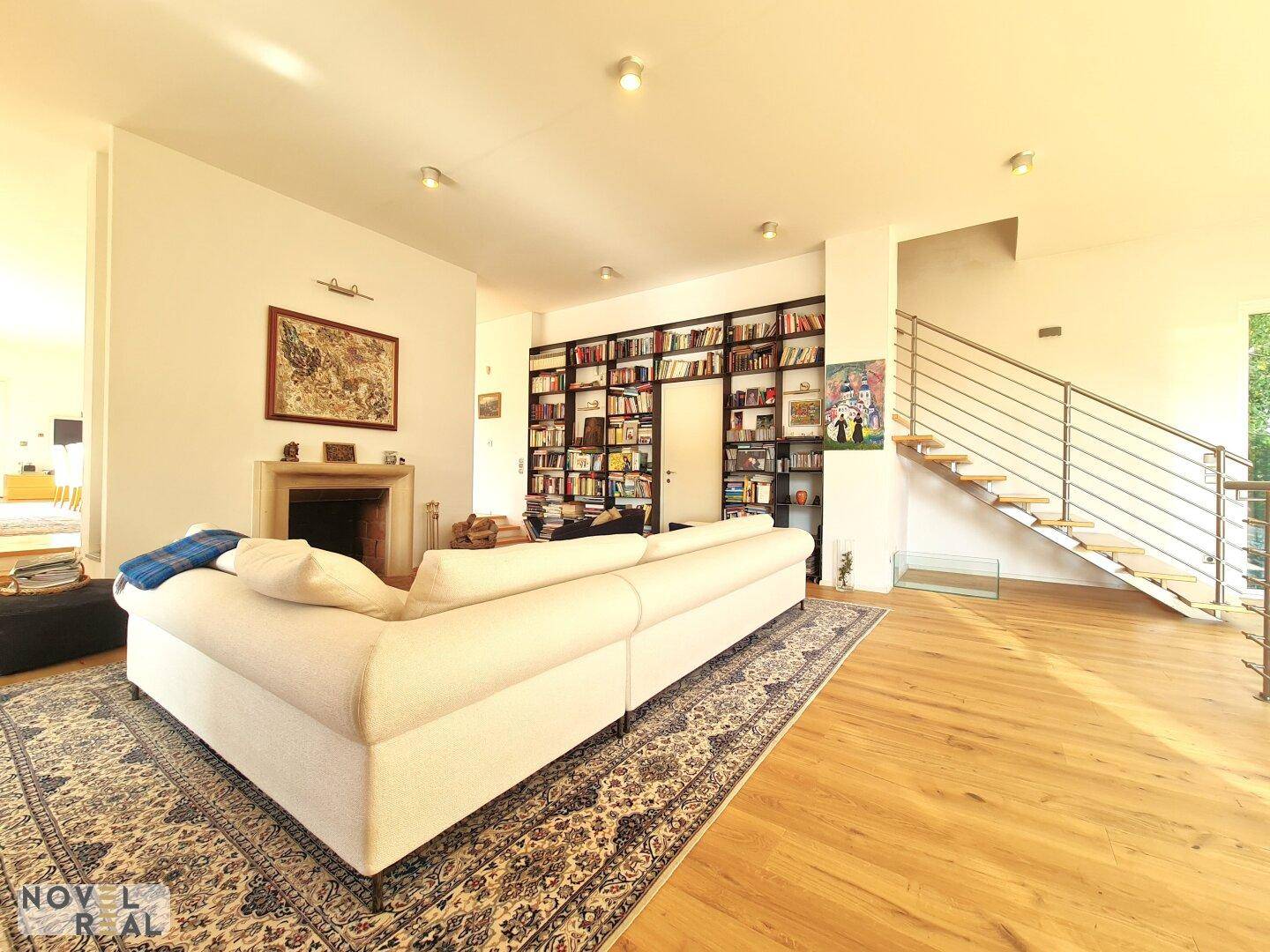 Gemütliches Wohnzimmer mit Kamin, großem Sofa und einer beeindruckenden Bücherwand.