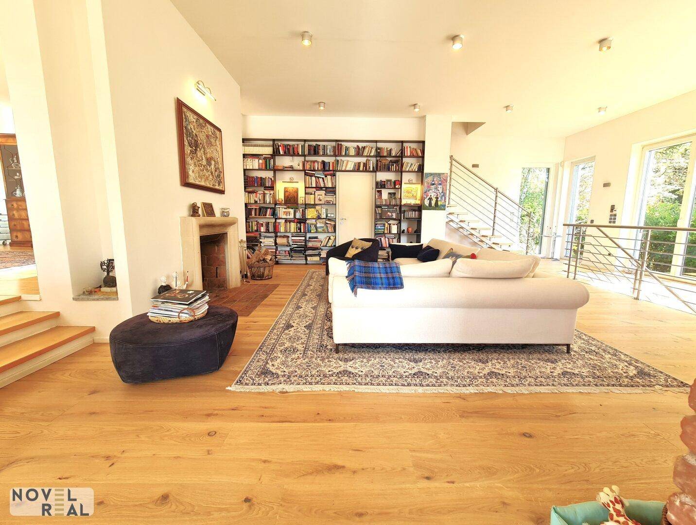 Helles Wohnzimmer mit Kamin, bequemer Couch und einer umfangreichen Bücherwand.