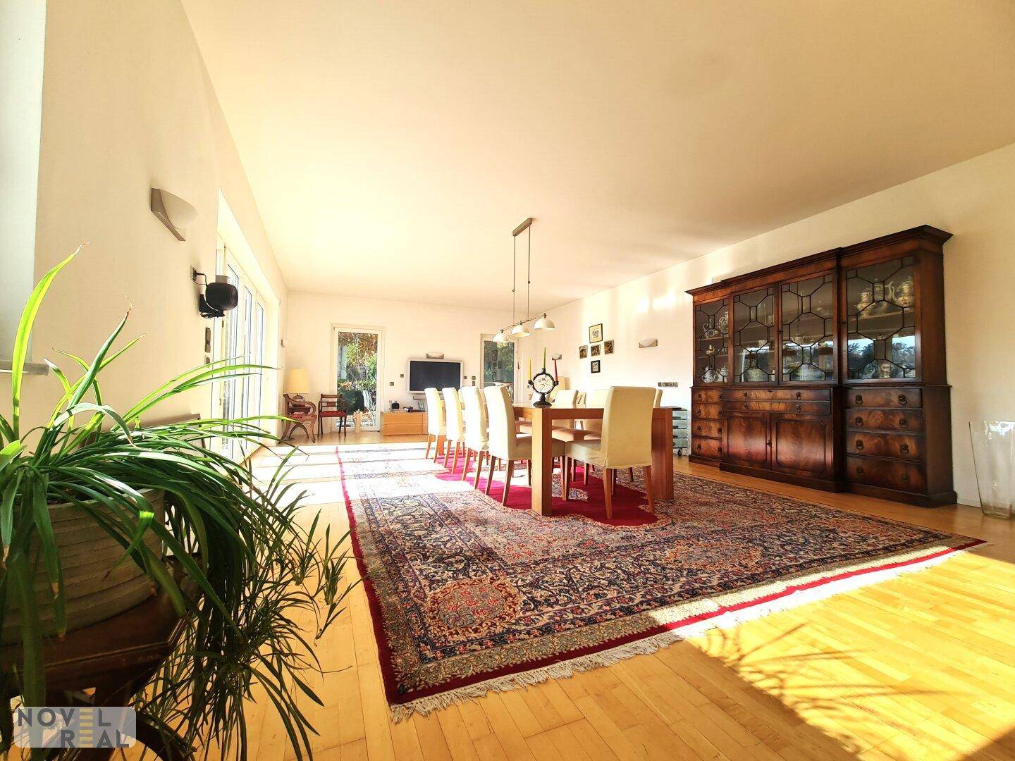 Geräumiger Essbereich mit großem Holztisch, Teppich und klassischem Sideboard.