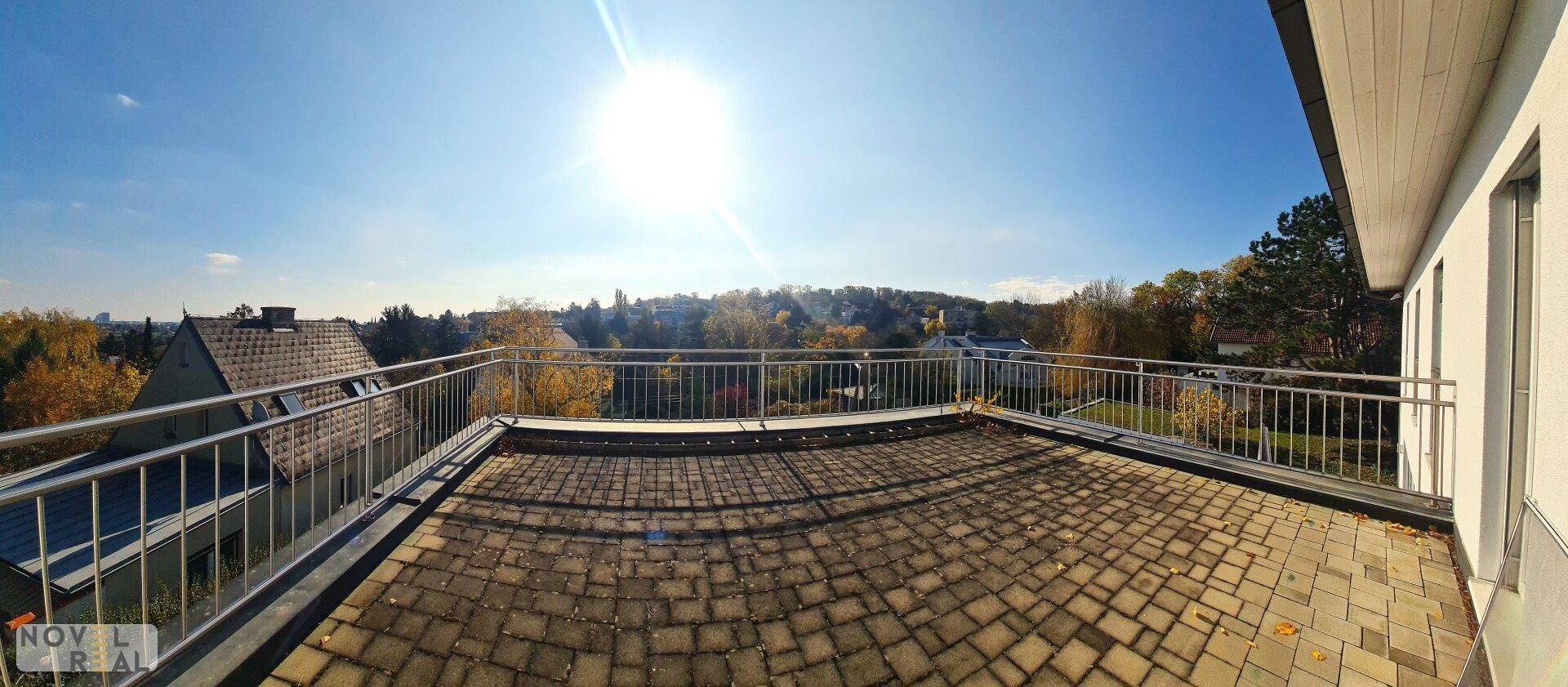 Große Dachterrasse mit gepflastertem Boden und weitem Blick über die Umgebung.