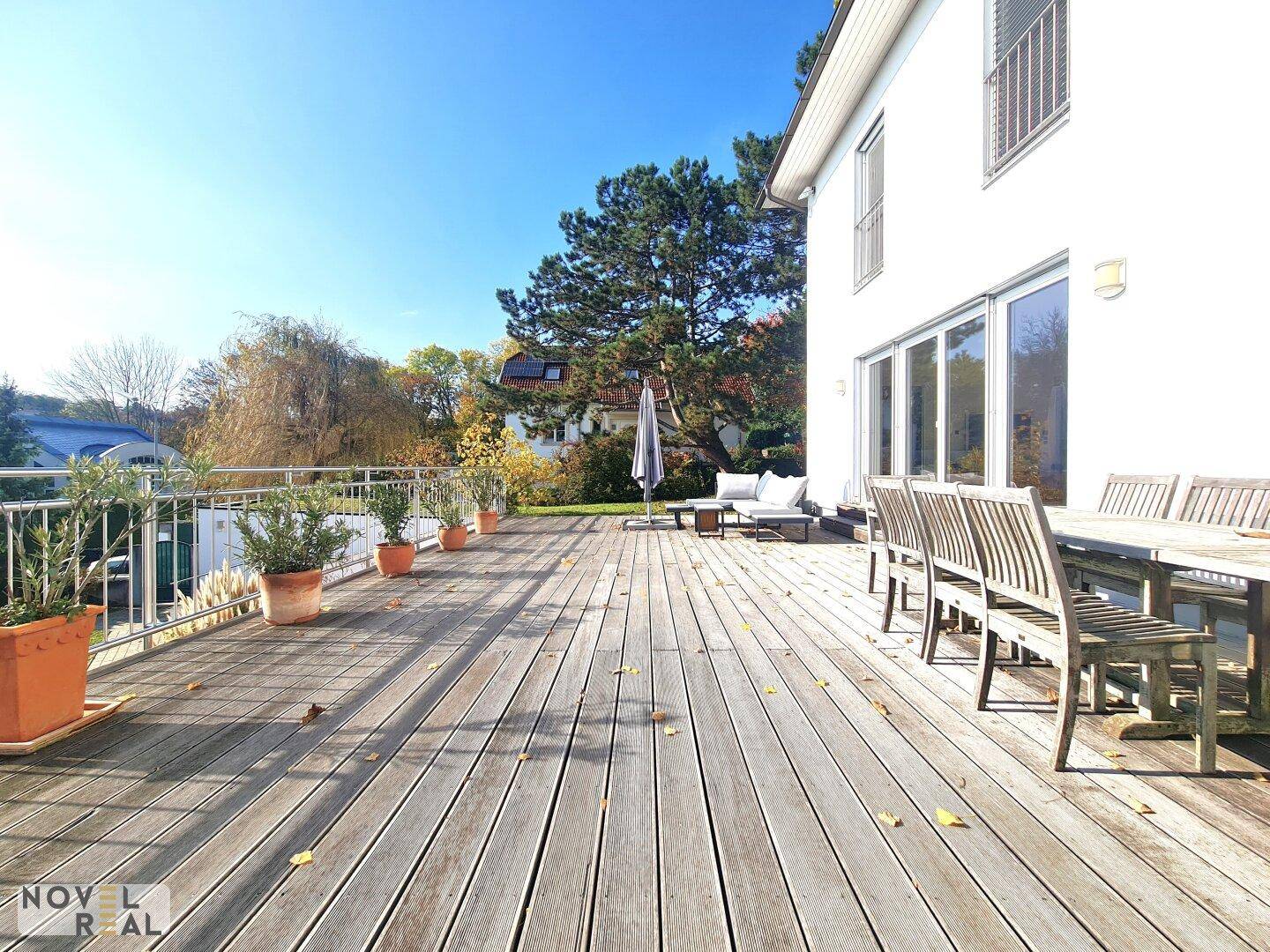 Weitläufige Holzterrasse mit Esstisch und Lounge-Möbeln, ideal für Mahlzeiten im Freien.