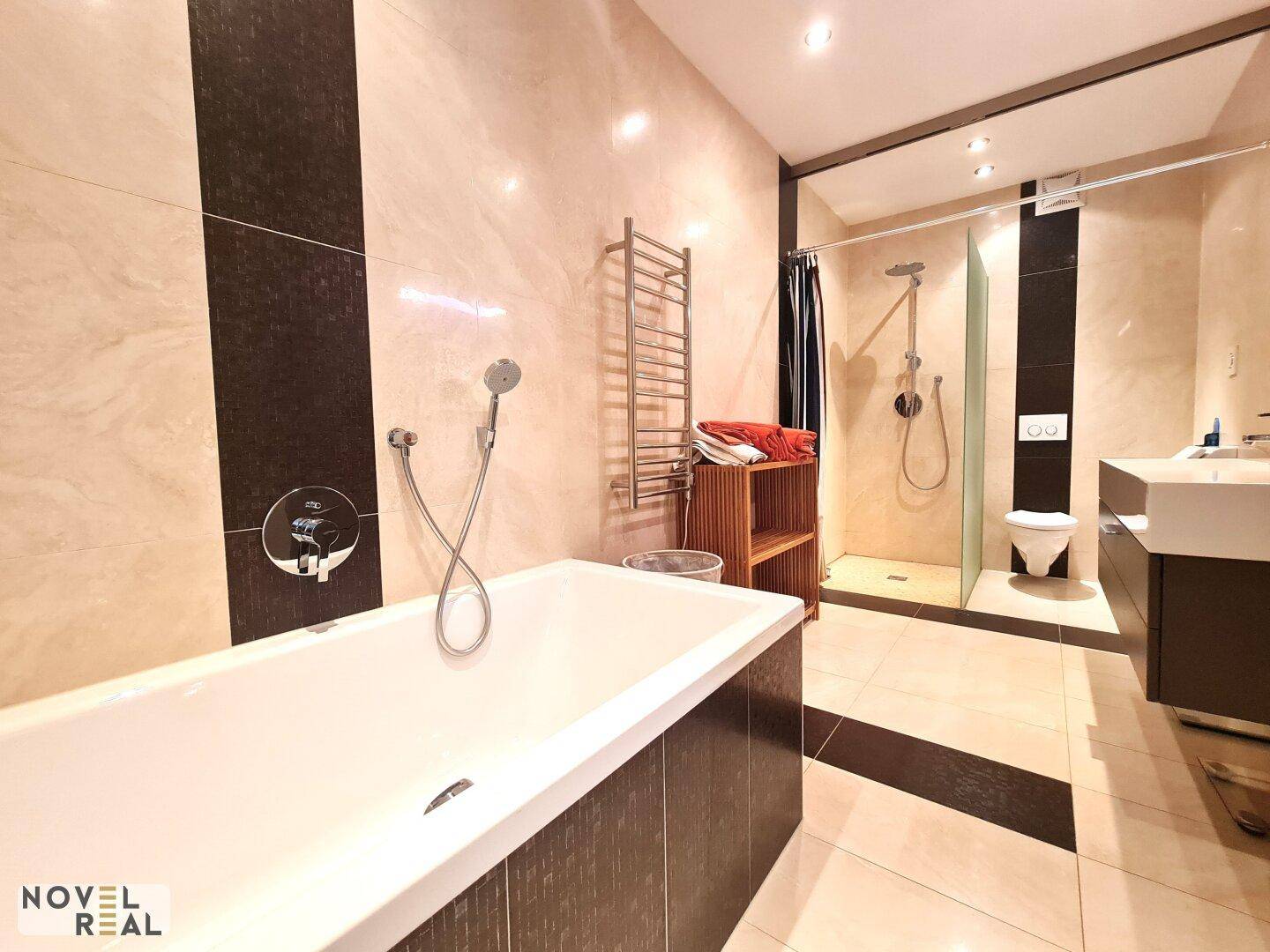 Modernes Badezimmer mit Badewanne, begehbarer Dusche und eleganten Fliesen.