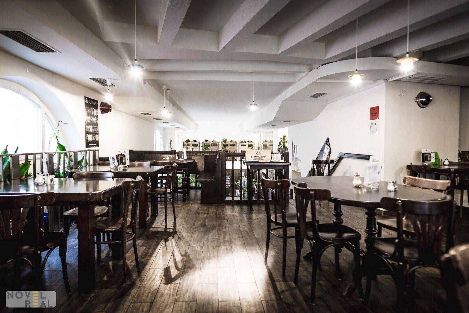 Geräumiger Restaurantbereich mit Holztischen, Stühlen und Holzboden, unter einer Decke mit Balken.