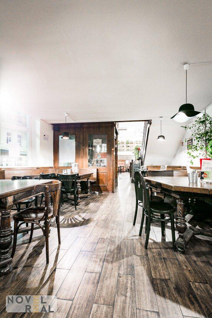 Gemütlicher Restaurantbereich mit Holztischen, Stühlen und Holzboden, beleuchtet von Hängelampen.