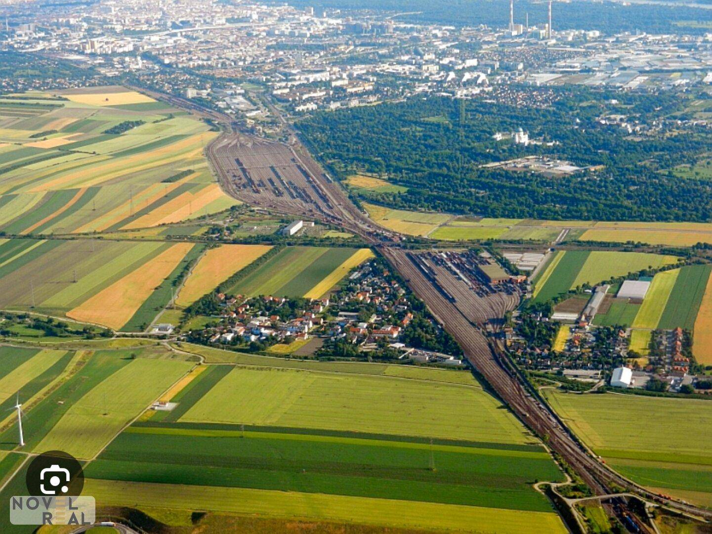 Luftaufnahme einer weiten Landschaft mit Feldern, einem Rangierbahnhof und einer kleinen Siedlung.