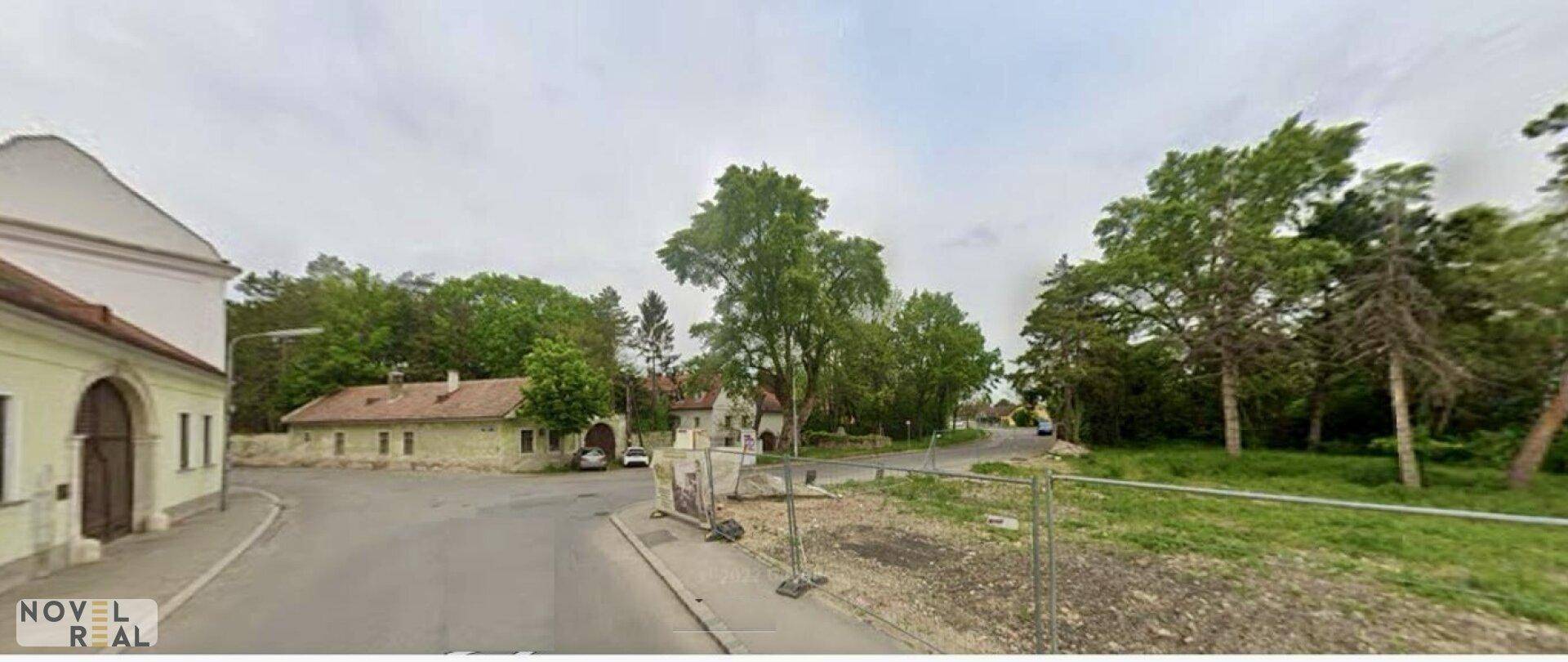Weitläufiges Grundstück mit angrenzender Straße und älteren Gebäuden, umgeben von viel Grün.