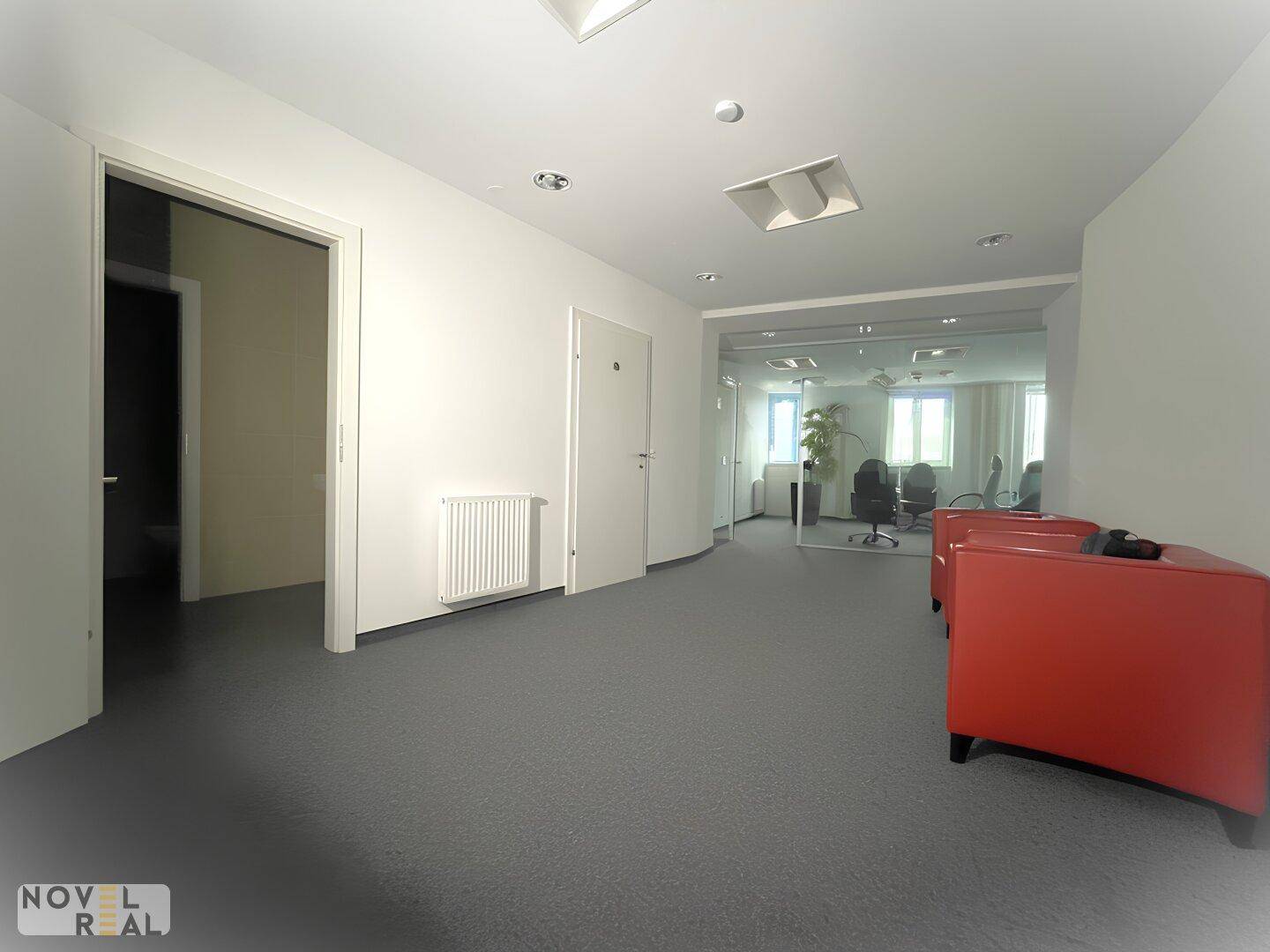 Langer Flur mit Teppichboden, Heizkörper und Zugang zu mehreren Büros mit Glaswänden.