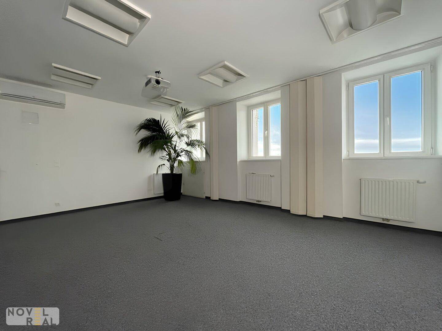 Heller Büroraum mit Teppichboden, Klimaanlage und großen Fenstern für viel Tageslicht.