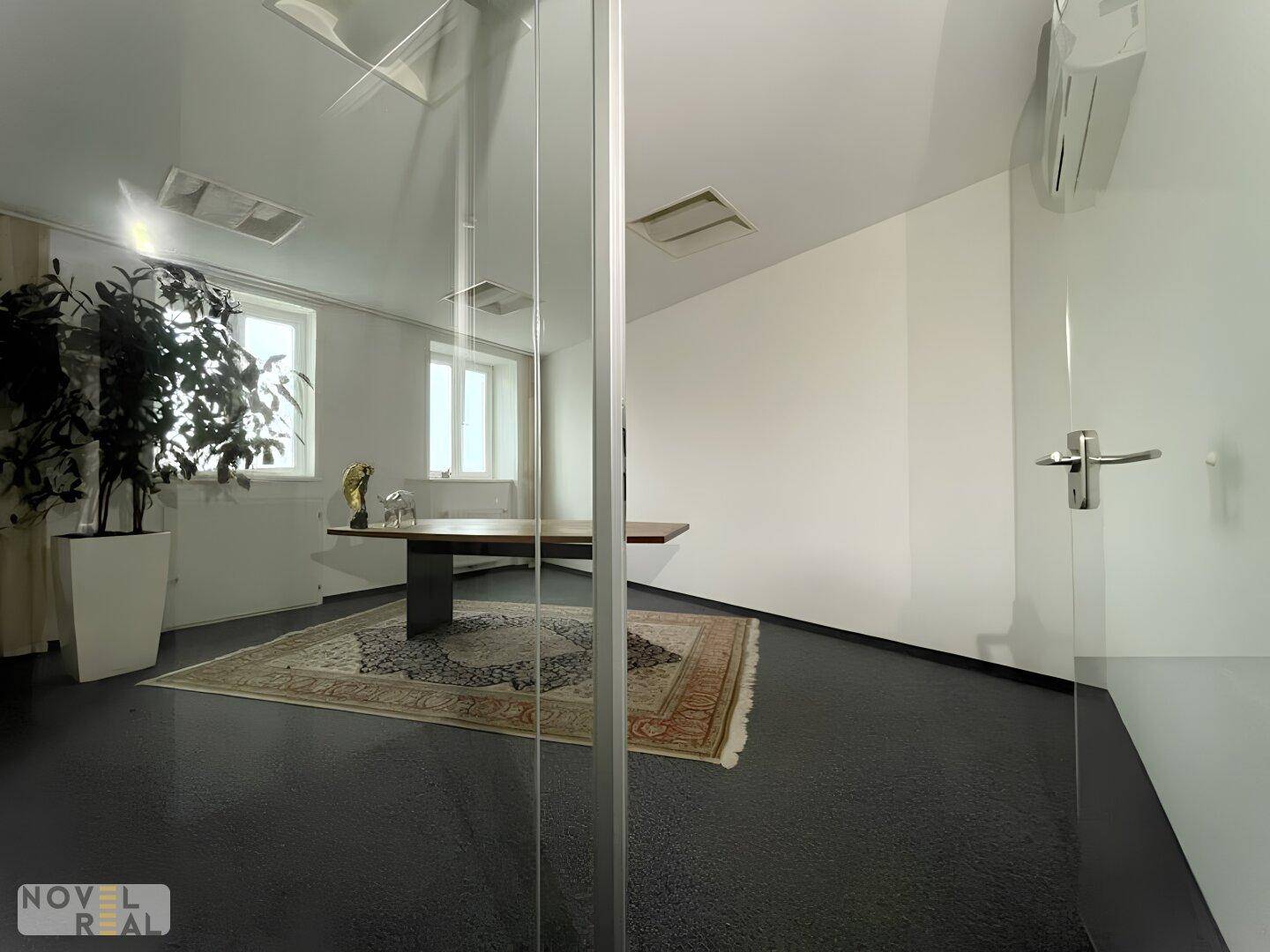 Elegantes Büro mit Teppichboden, großem Holztisch und Glaswänden für offene Atmosphäre.