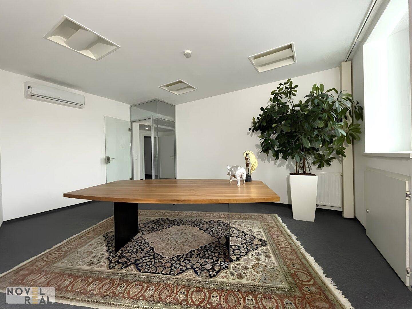 Modernes Büro mit großem Holztisch, Teppichboden und Klimaanlage für angenehmes Klima.