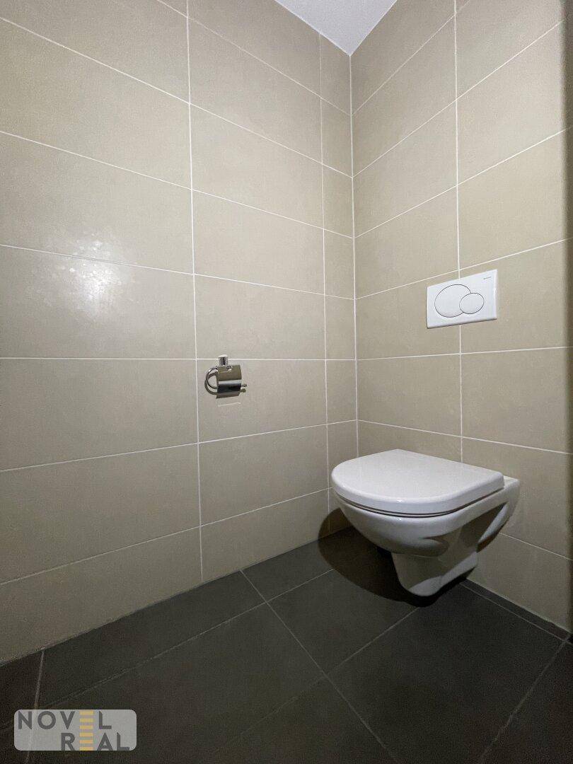 Separate Toilette mit beigen Wandfliesen und wandhängendem WC für einfache Reinigung.