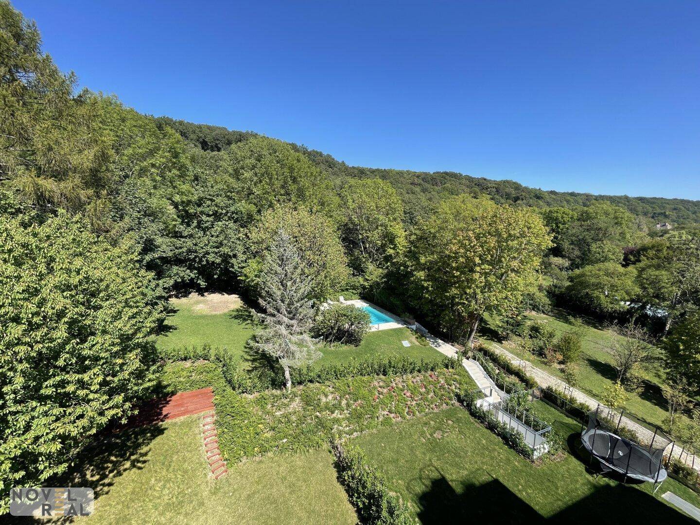 Weitläufiges grünes Anwesen mit Pool, umgeben von Wäldern und Hügeln, bietet viel Platz im Freien.