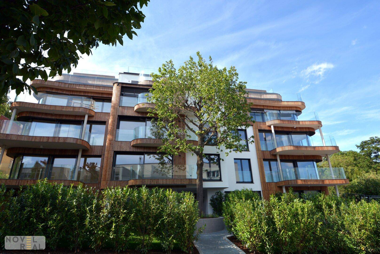 Moderne Wohnhausfassade mit Holzverkleidung, großen Glasfronten und eleganten Balkonen.