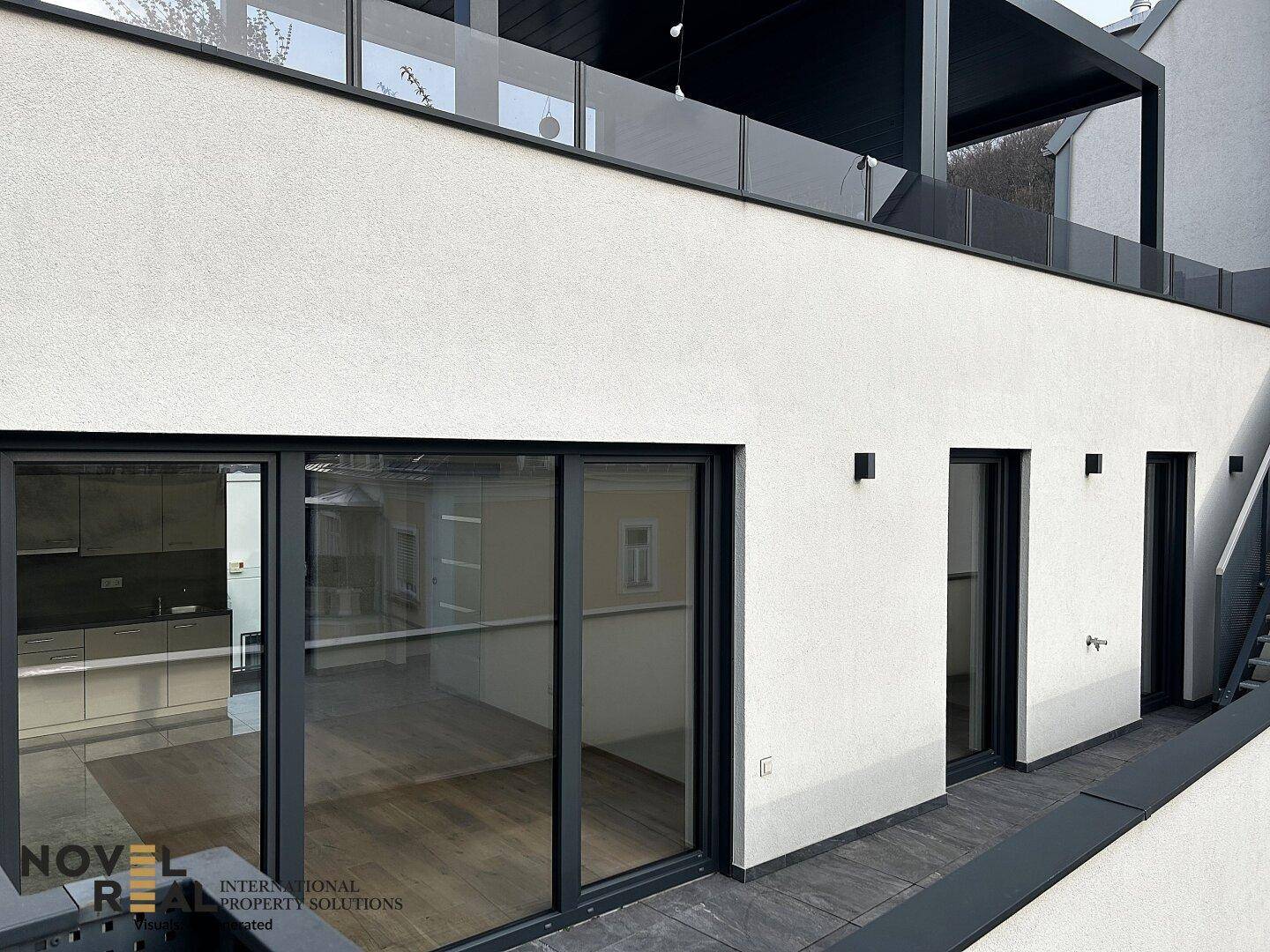 Geräumige Terrasse mit modernen Glasgeländern und Blick auf die Umgebung.