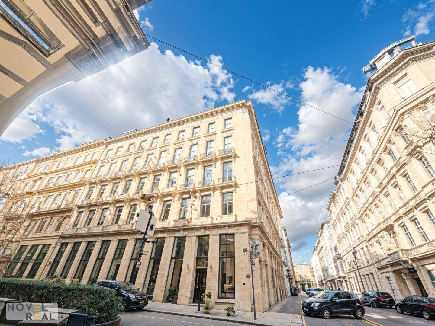 Elegantes Stadtgebäude mit historischer Architektur und vielen Fenstern an einer belebten Straße.