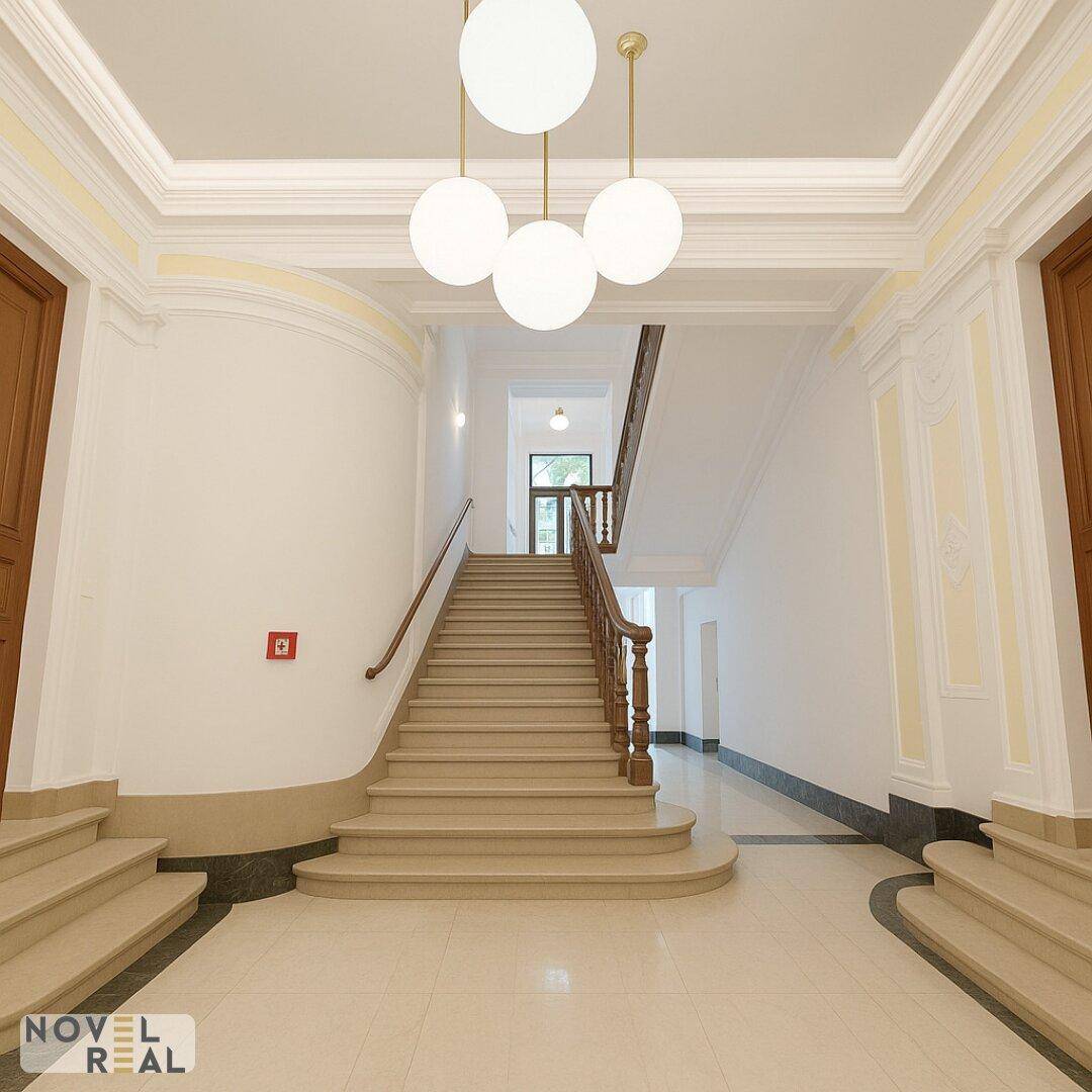 Elegantes Treppenhaus mit Marmorboden, Stuckelementen und klassischer Beleuchtung.