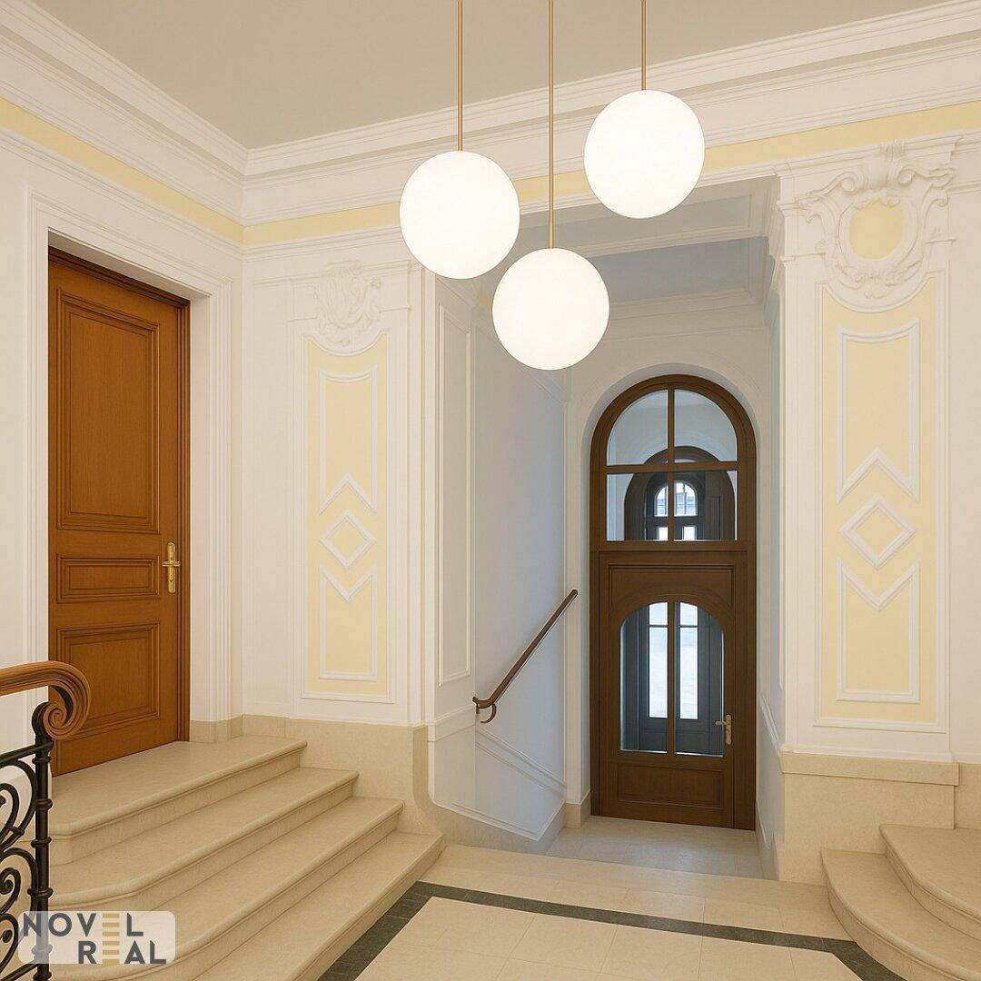 Elegantes Treppenhaus mit Stuckverzierungen, Holztüren und modernen Pendelleuchten.