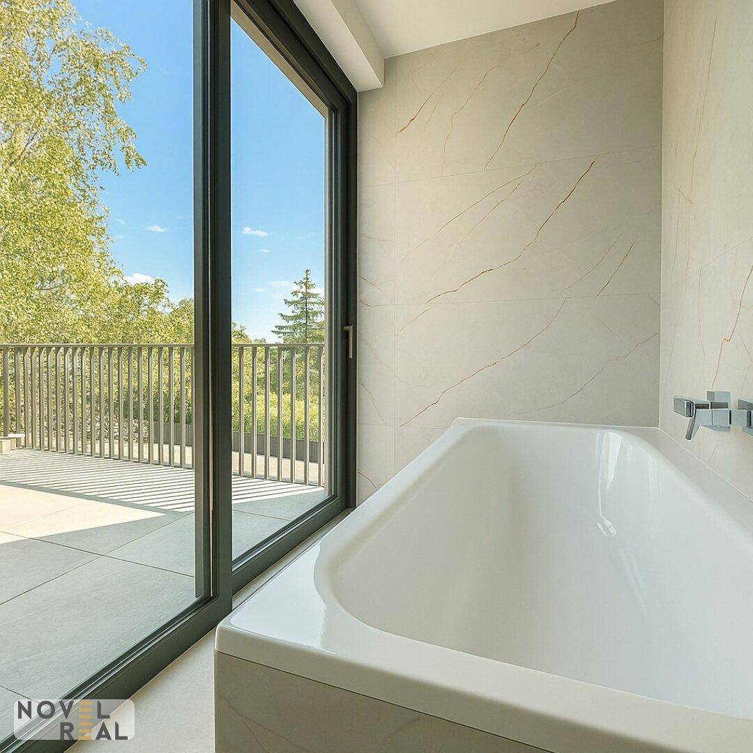 Badezimmer mit Badewanne und großem Fenster, das Zugang zu einem Außenbereich bietet.