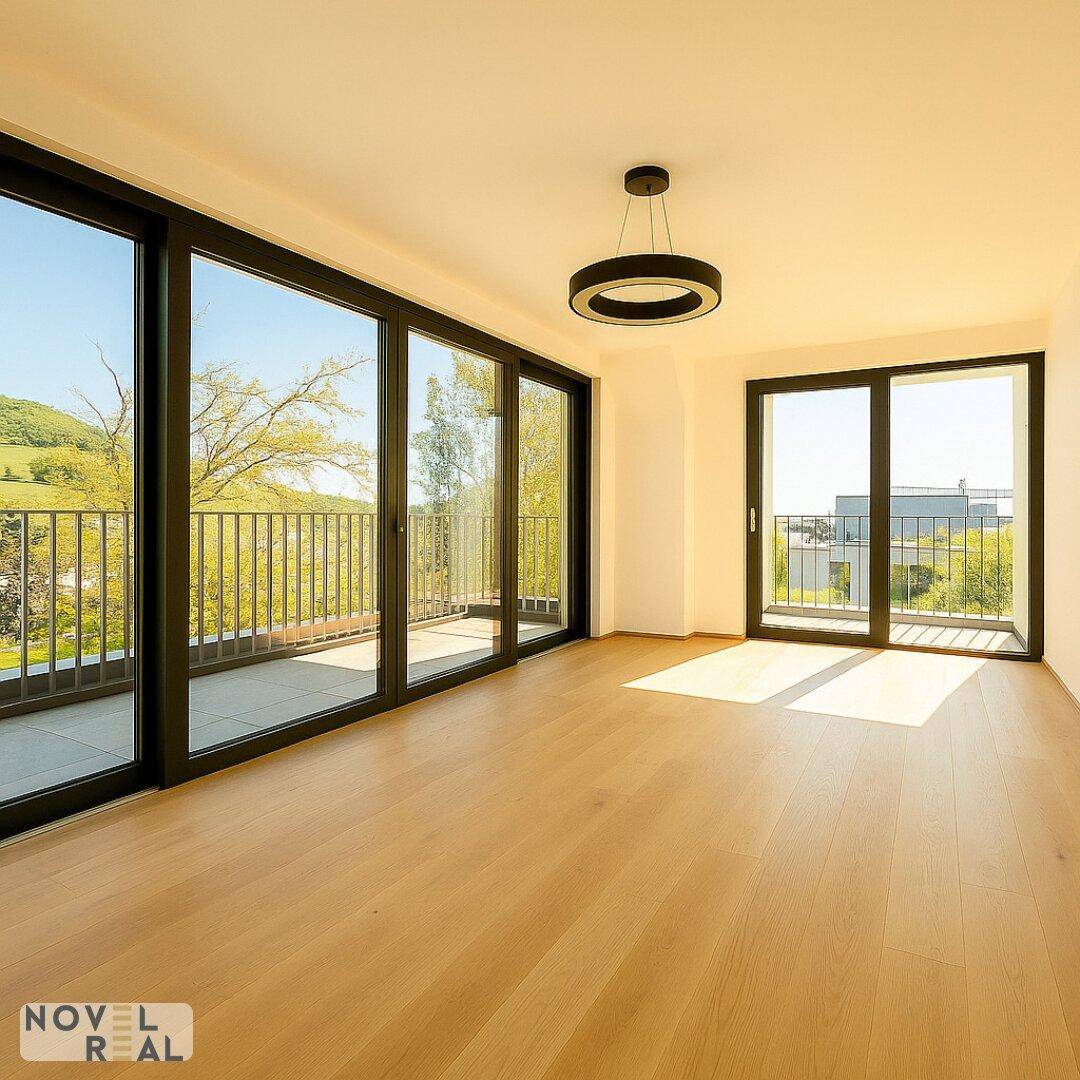 Helles Wohnzimmer mit Holzboden und breitem Zugang zu einem Balkon mit schöner Aussicht.