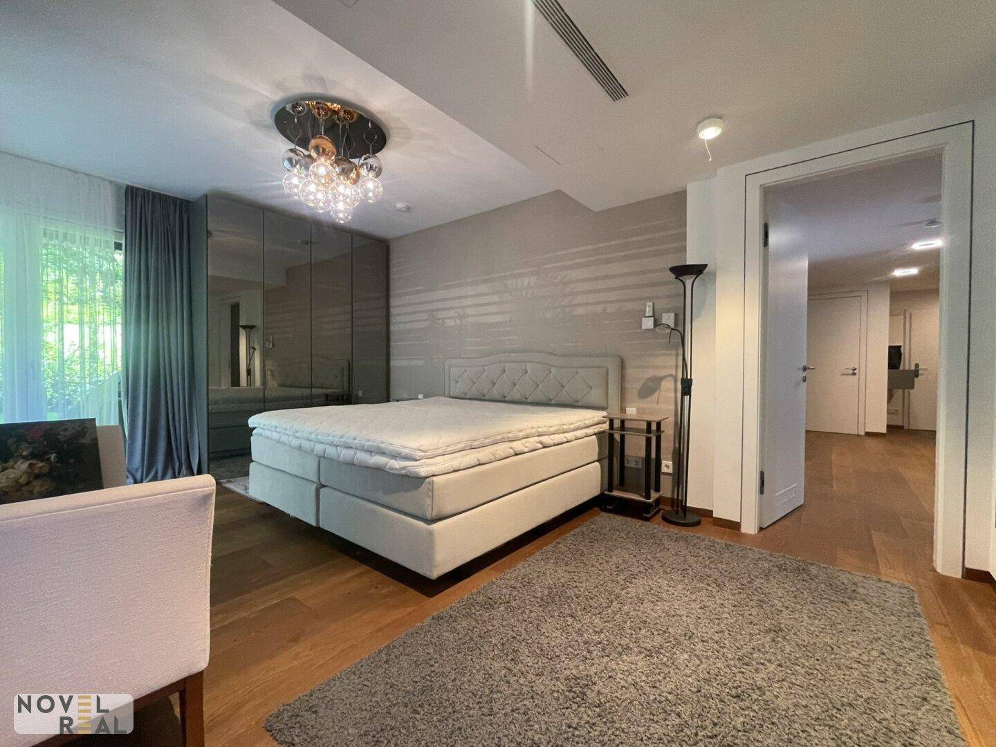 Elegantes Schlafzimmer mit Boxspringbett, stilvoller Wandgestaltung und Zugang zu weiteren Räumen.