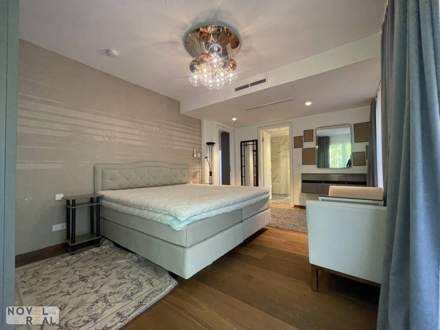 Helles Schlafzimmer mit Zugang zu einem modernen Badezimmer, ausgestattet mit Marmorfliesen.