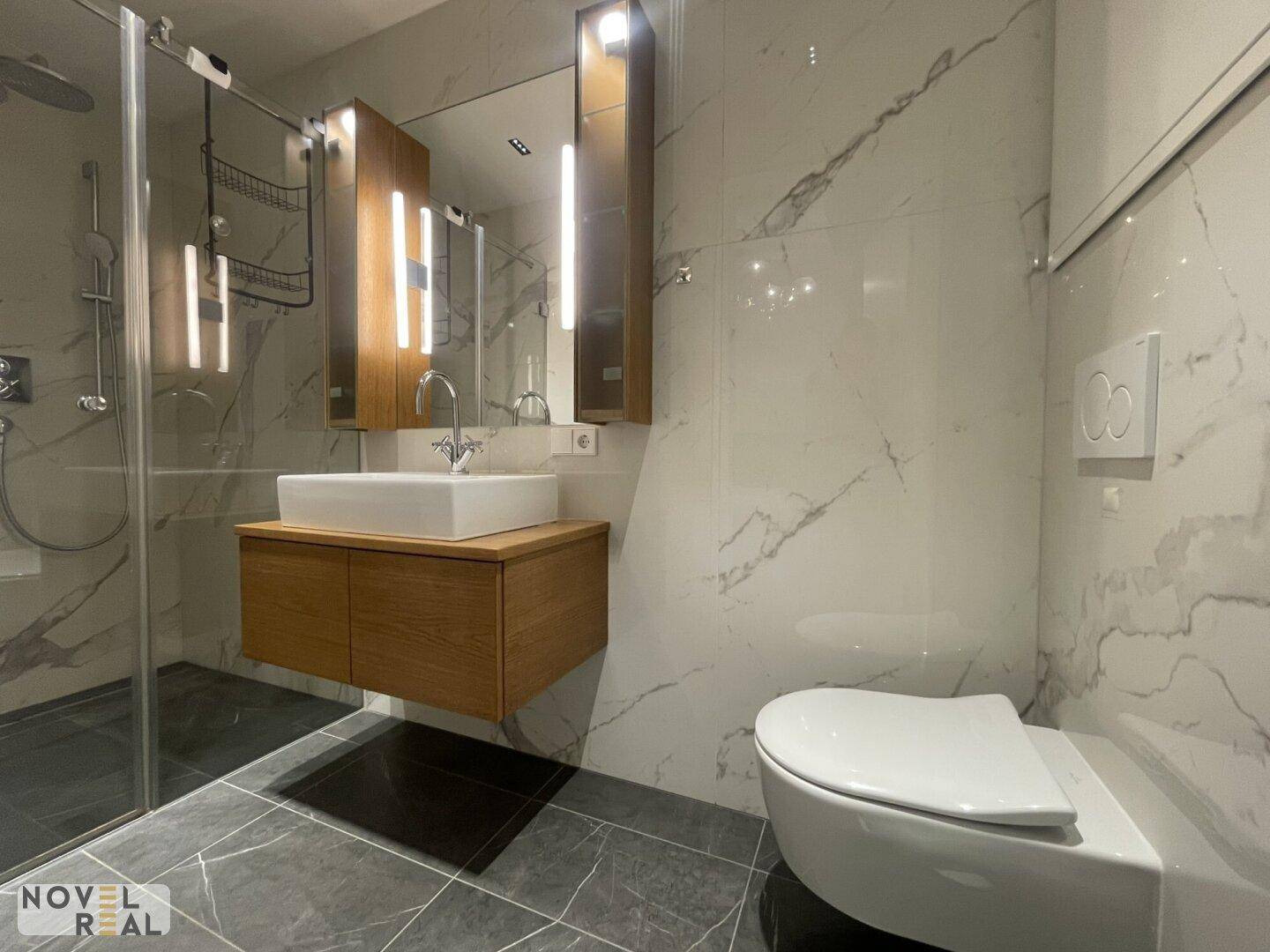 Stilvolles Badezimmer mit Waschtisch, wandhängendem WC und begehbarer Dusche, in Marmoroptik.