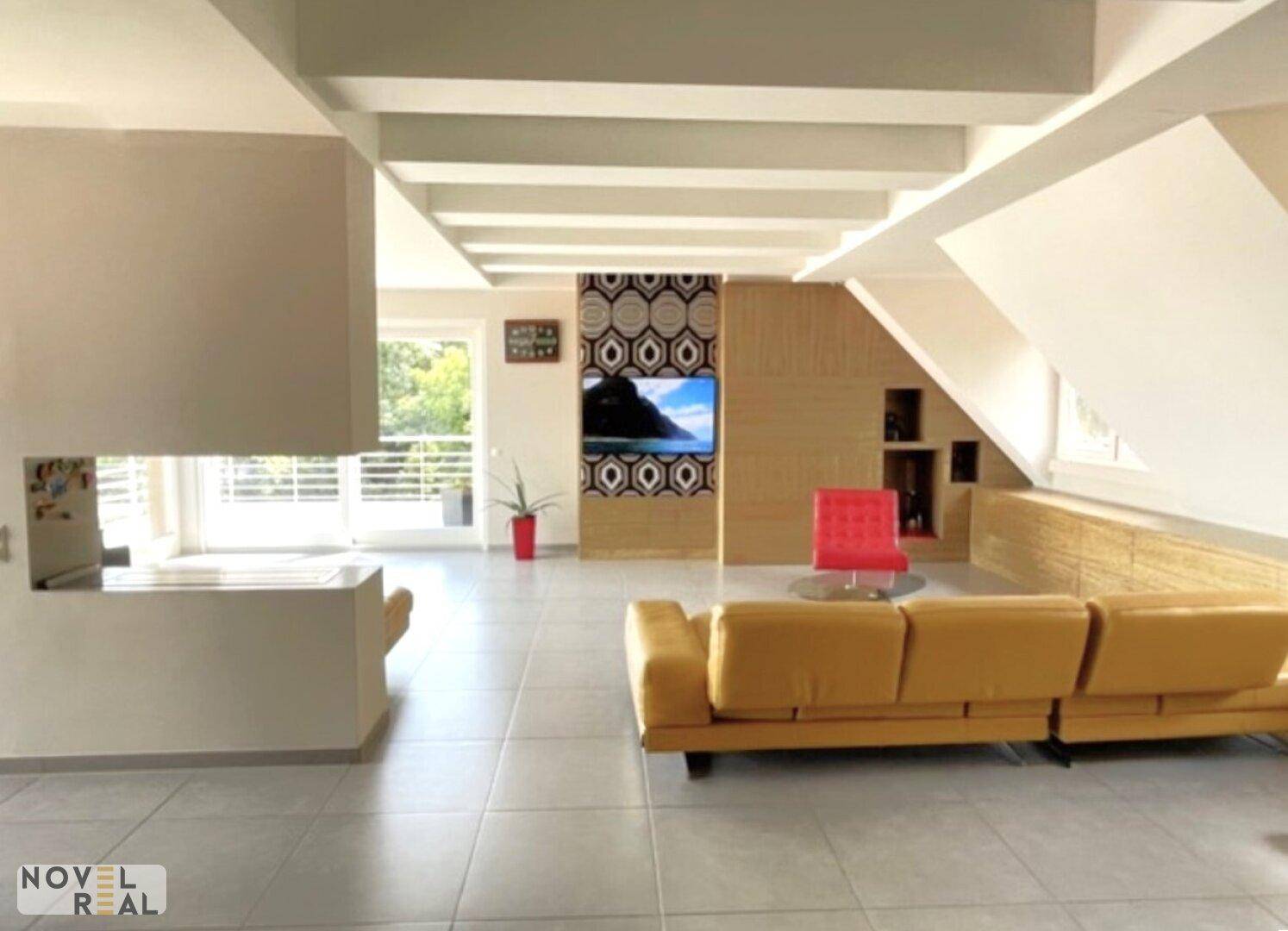 Geräumiges Wohnzimmer mit gelbem Sofa, Kamin und modernem TV-Bereich unter Dachschrägen.