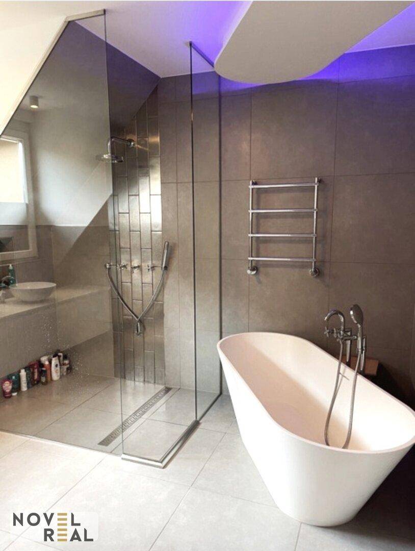 Modernes Badezimmer mit freistehender Badewanne, großer begehbarer Dusche und stilvollen Fliesen.