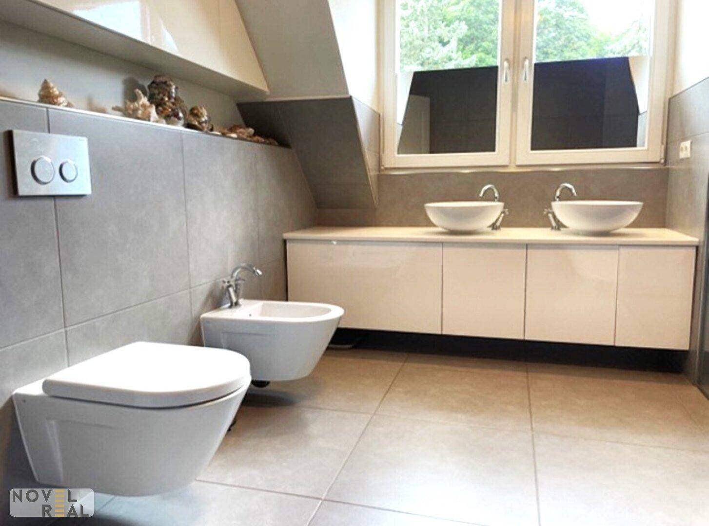 Geräumiges Badezimmer mit zwei Waschbecken, Bidet und modernen Armaturen.