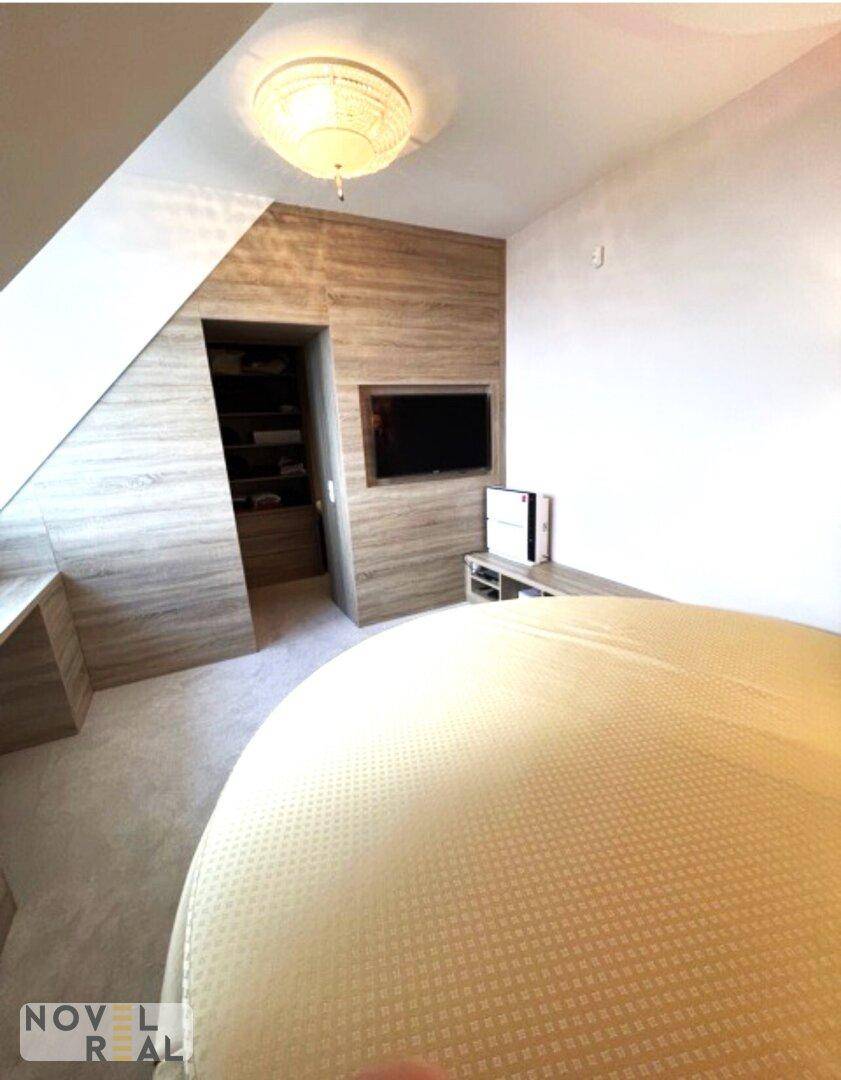 Schlafzimmer mit rundem Bett, integrierten Schränken und Fernseher unter der Dachschräge.