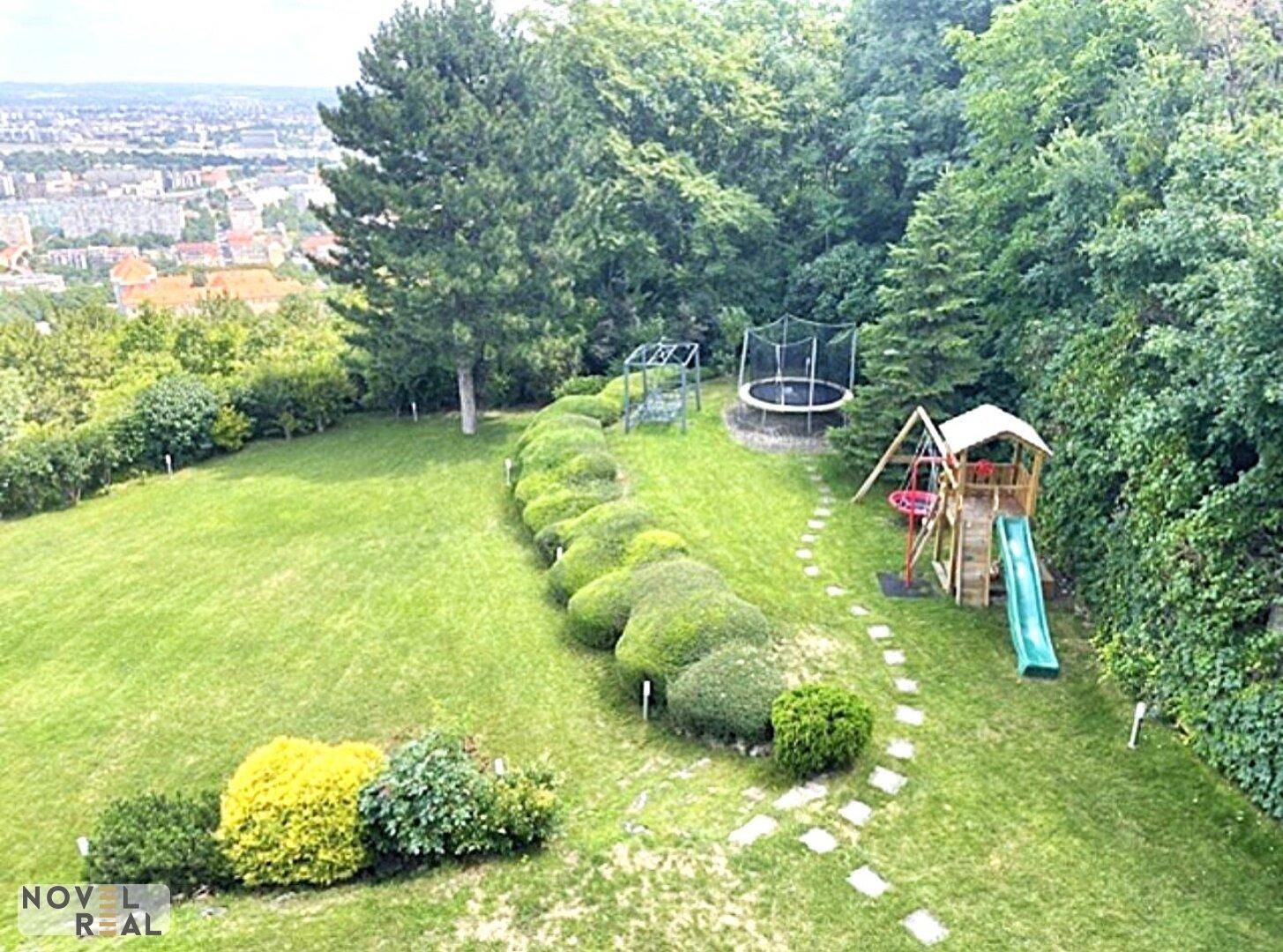 Großer Garten mit Trampolin, Spielplatz und weitem Blick über die Stadt.