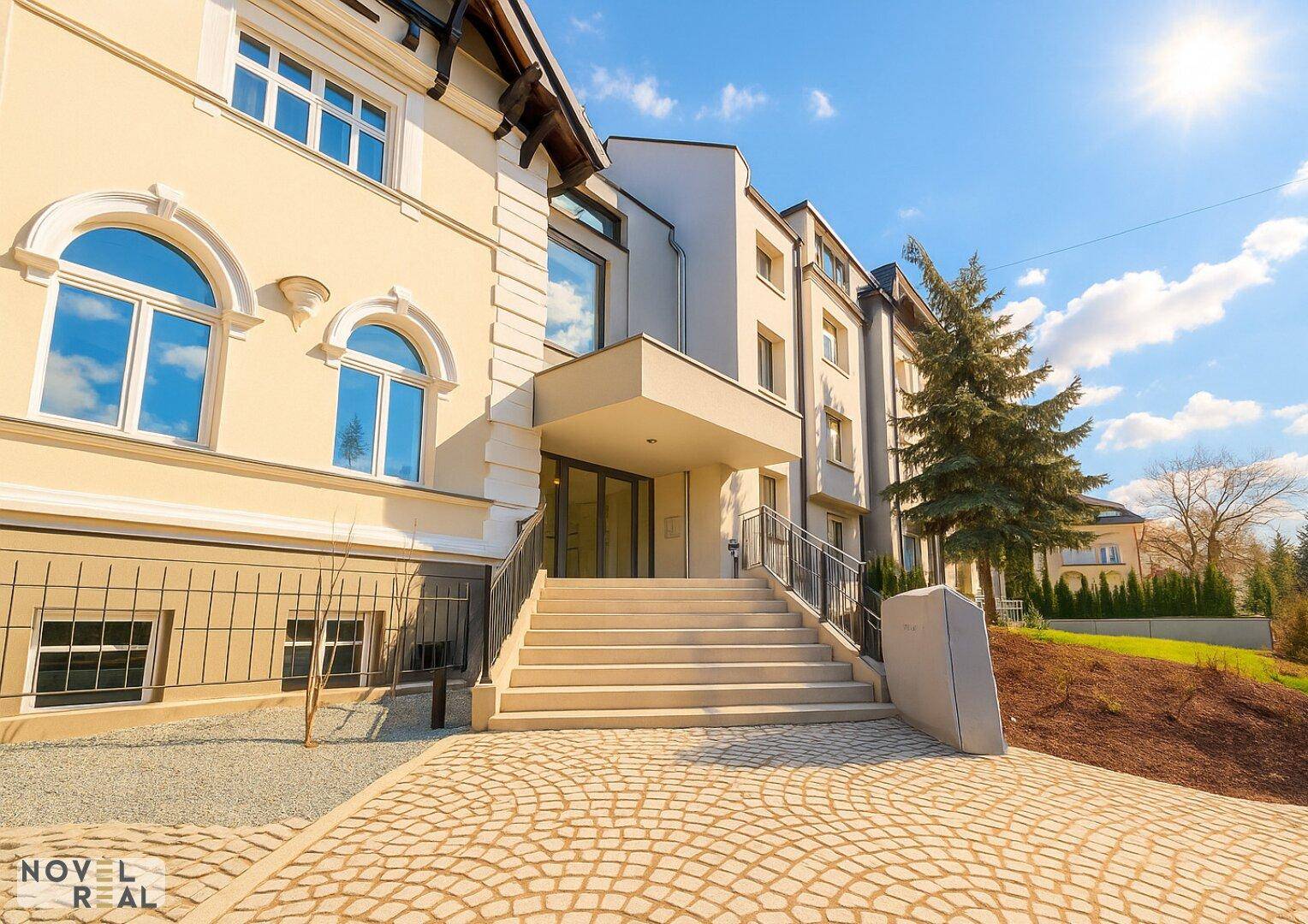 Elegantes Gebäude mit repräsentativem Eingangsbereich, breiter Steintreppe und gepflastertem Vorplatz.