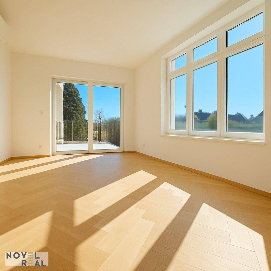 Lichtdurchfluteter Raum mit Fischgrätparkett und Zugang zu einem Balkon, ideal als Wohn- oder Schlafzimmer.