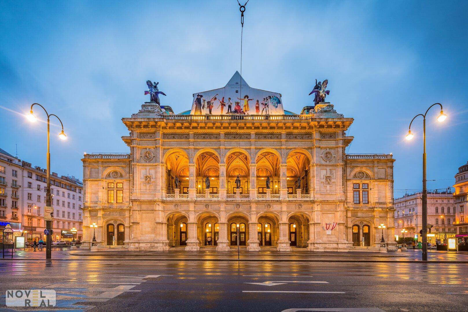 Die Wiener Staatsoper bei Dämmerung, ein prächtiges Gebäude mit historischer Architektur und beleuchteten Bögen.
