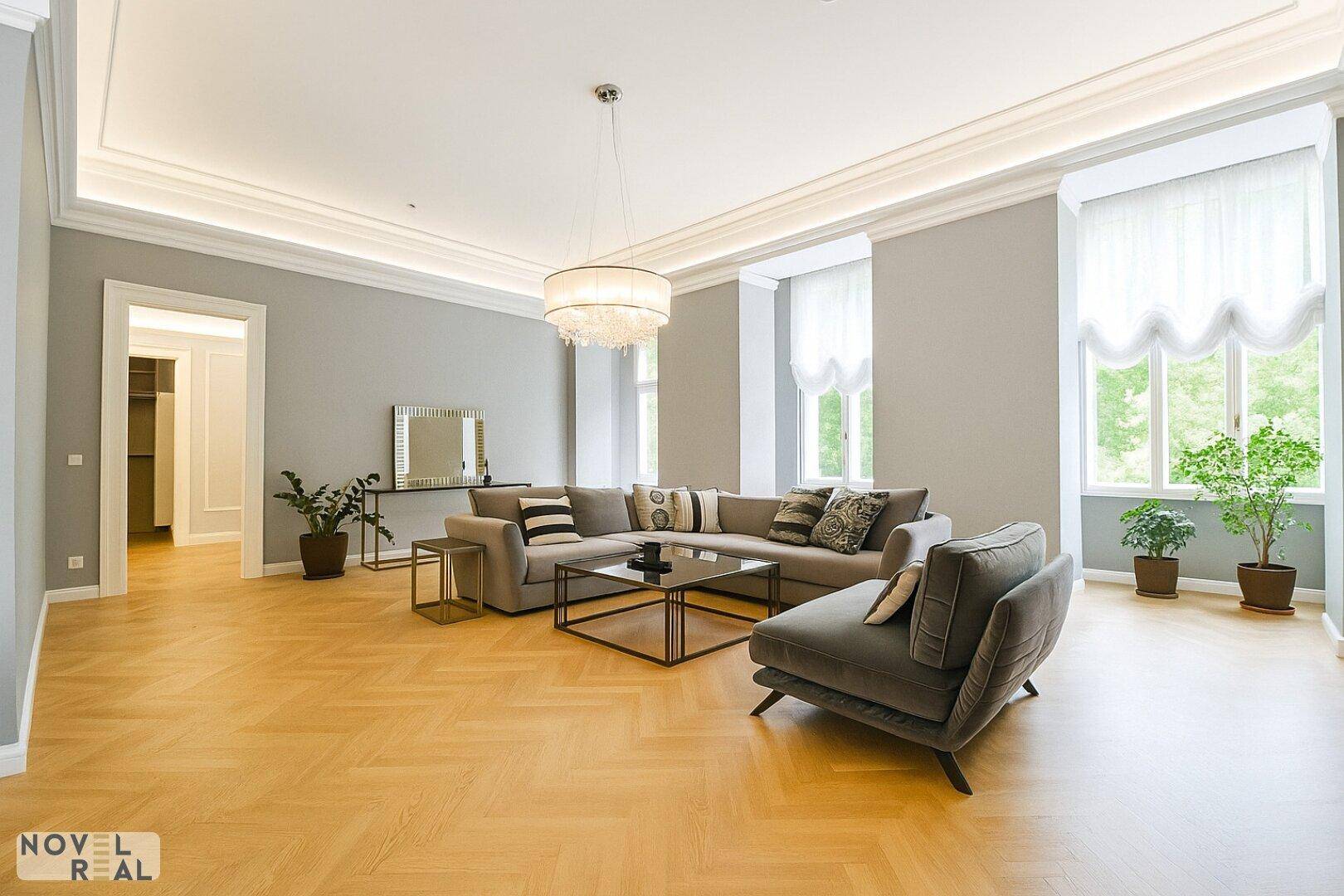 Elegantes Wohnzimmer mit Fischgrätparkett, bequemer Couch und stilvoller Beleuchtung.