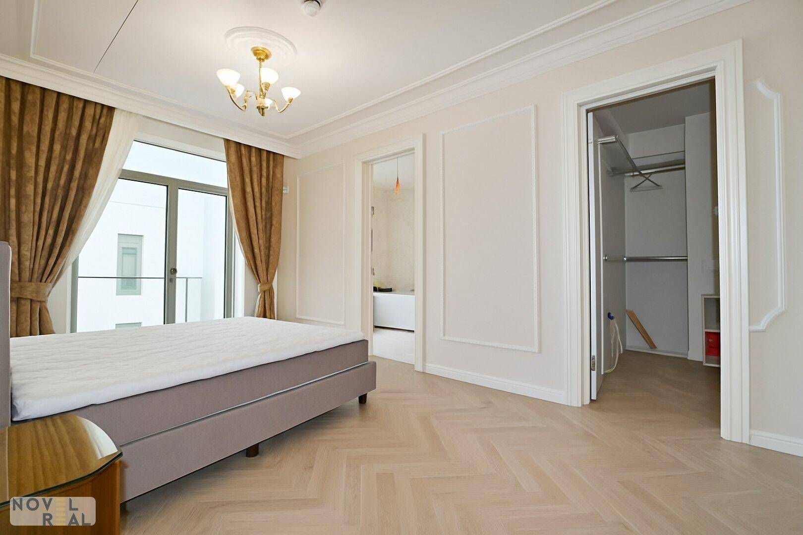 Helles Schlafzimmer mit Fischgrätparkett und Zugang zu einem begehbaren Kleiderschrank.
