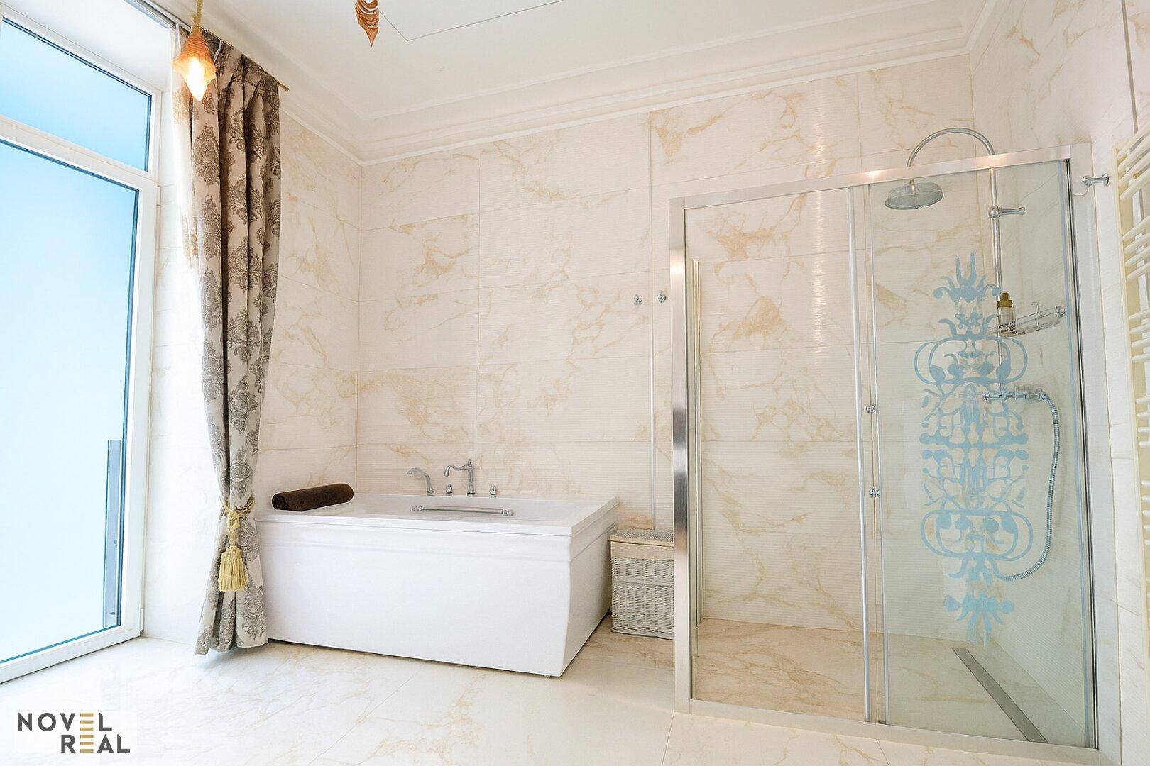 Luxuriöses Badezimmer mit Marmorfliesen, Badewanne und großer Duschkabine.