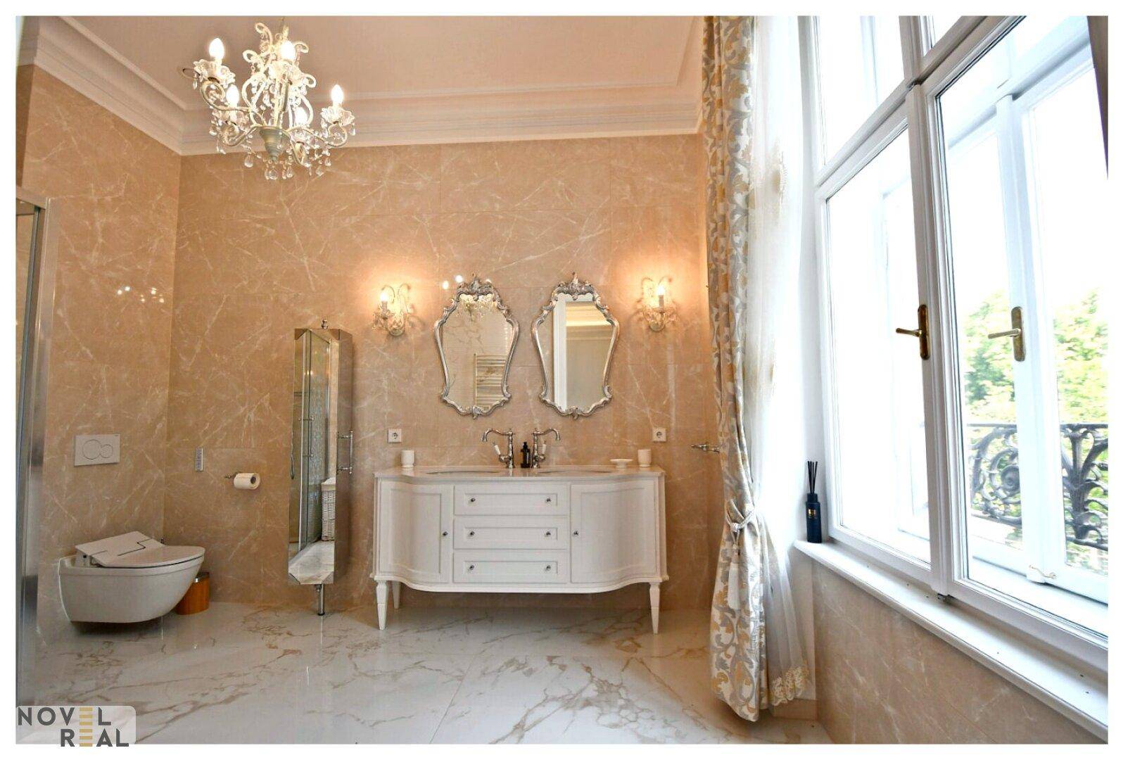 Elegantes Badezimmer mit Doppelwaschbecken, Marmorfliesen und großem Fenster.