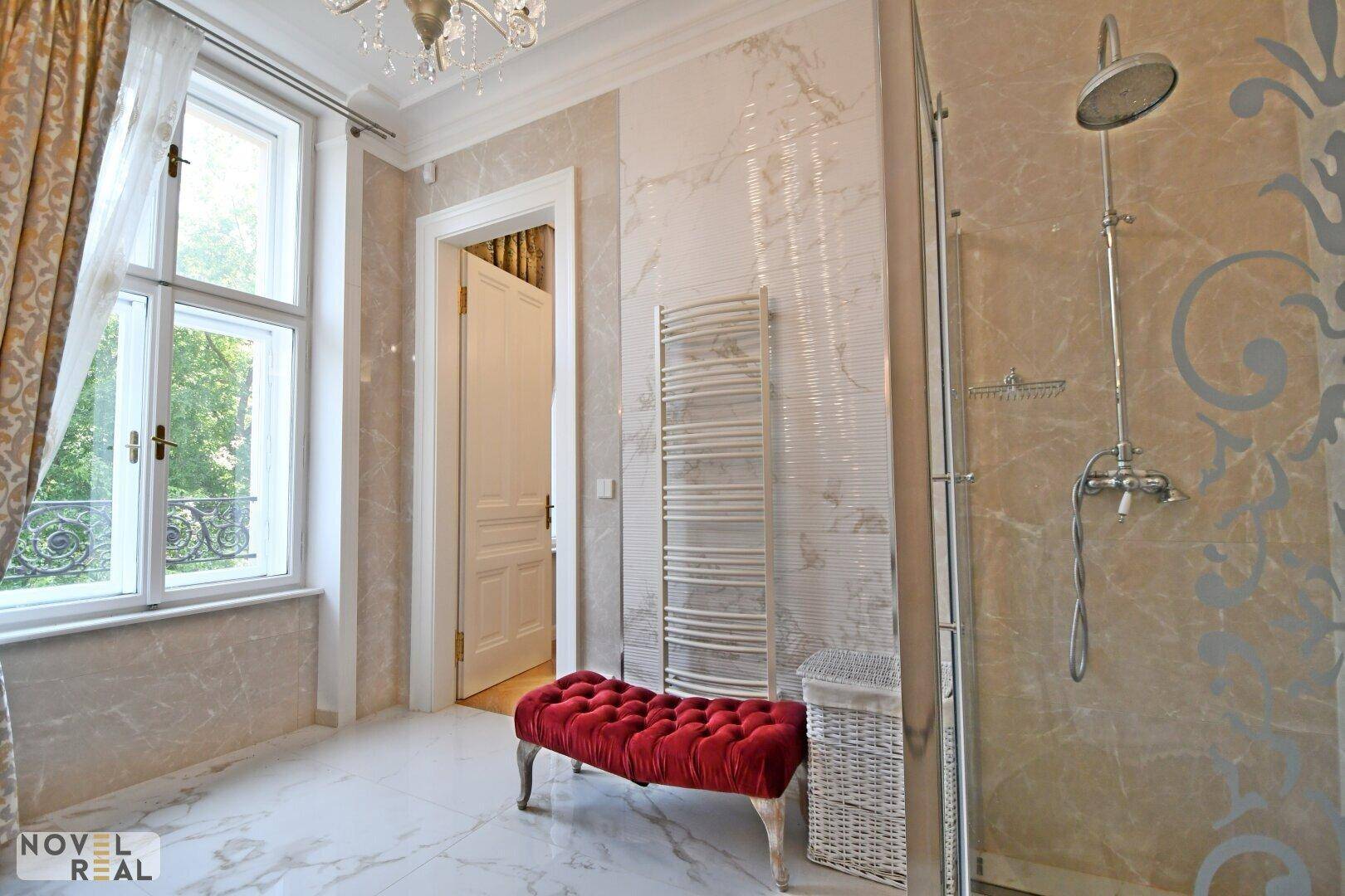 Helles Badezimmer mit Marmorfliesen, Duschbereich und beheiztem Handtuchhalter.