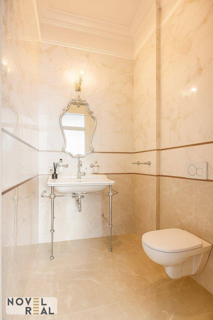 Elegantes Badezimmer mit klassischem Waschtisch, Wand-WC und hellen Marmorfliesen.