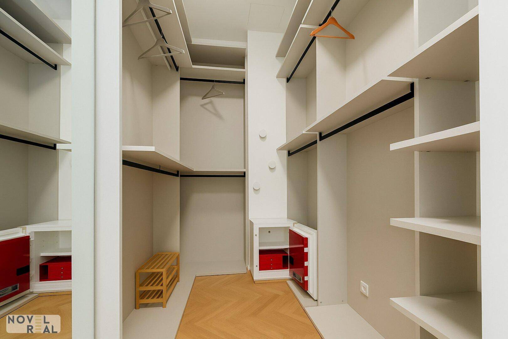 Geräumiger begehbarer Kleiderschrank mit Regalen, Kleiderstangen und integriertem Safe.