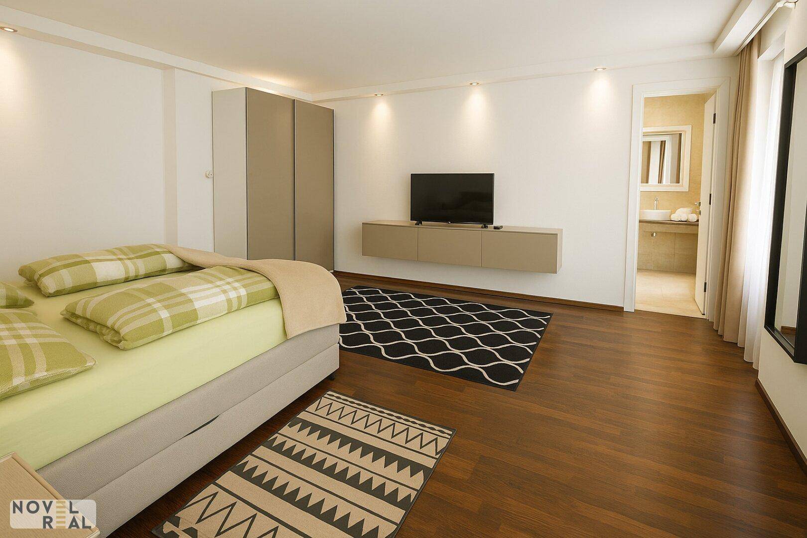 Schlafzimmer mit Bett, Einbauschränken und Blick auf das angrenzende Badezimmer.