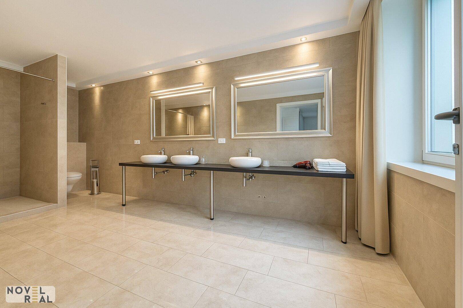 Modernes Badezimmer mit begehbarer Dusche, Doppelwaschbecken und Fenster.