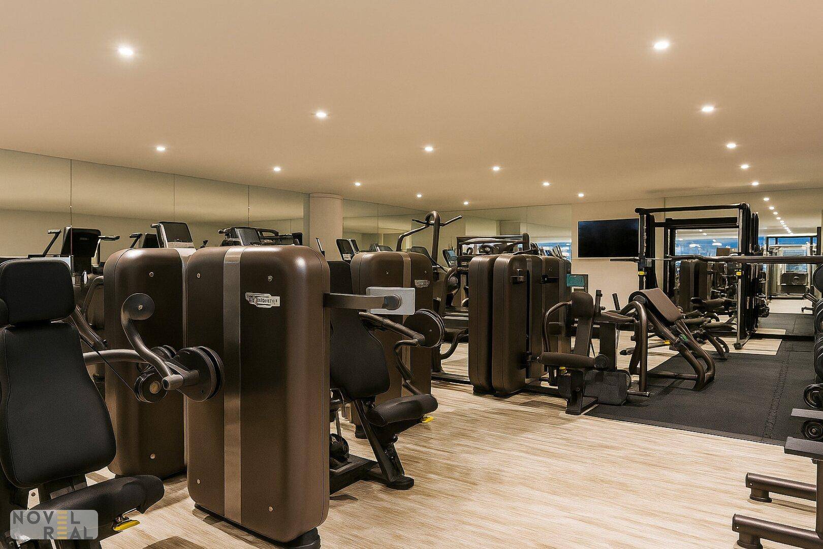 Moderner Fitnessraum mit einer Vielzahl von Trainingsgeräten und Spiegelwänden.