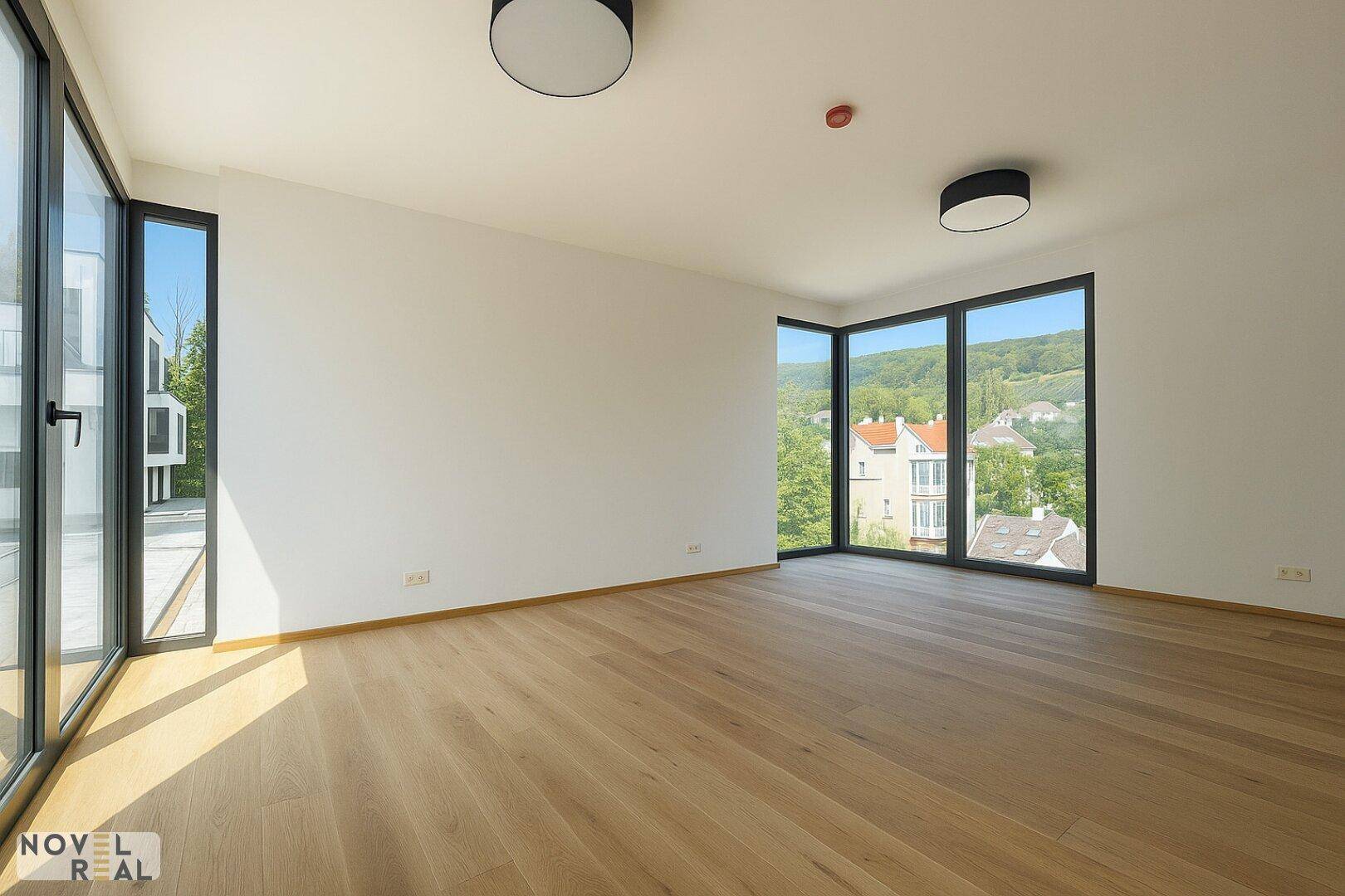 Heller Eckraum mit großen Fenstern und Panoramablick auf die grüne Landschaft und Nachbarschaft.