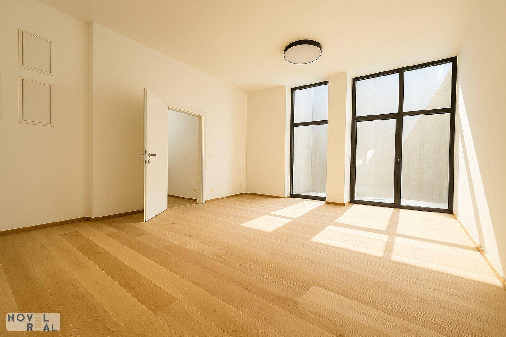Geräumiger, heller Raum mit Holzboden und hohen Fenstern, bietet vielseitige Gestaltungsmöglichkeiten.
