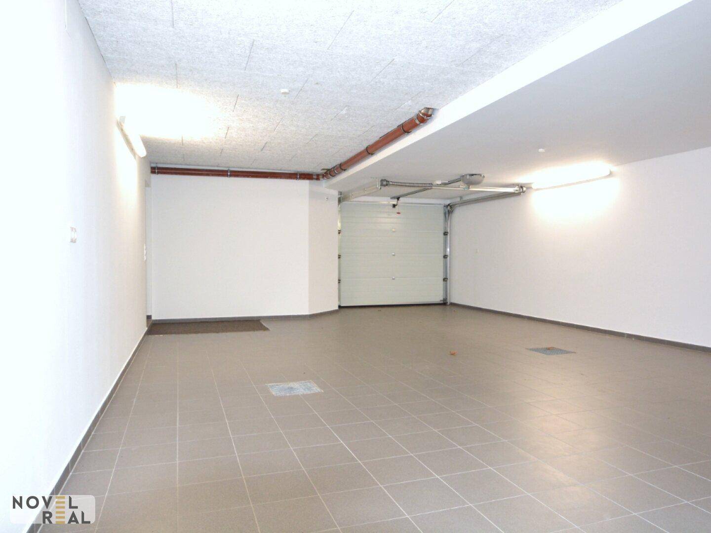 Geräumige Garage mit gefliestem Boden und automatischem Garagentor.