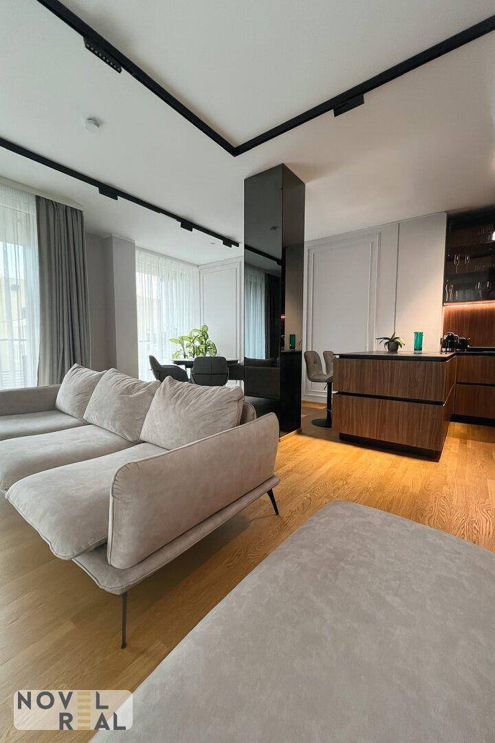 Heller Wohn- und Essbereich mit beigem Sofa, Holzboden und moderner Einrichtung.