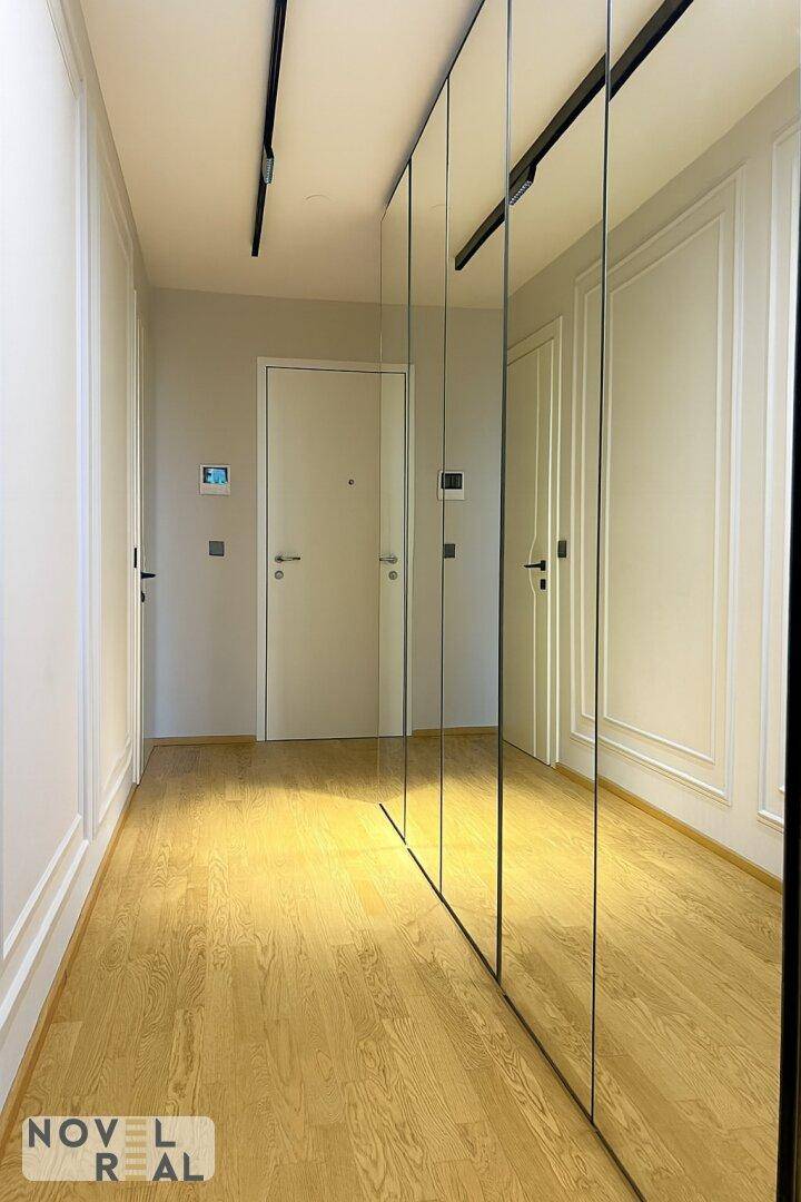 Heller Flur mit Spiegelschränken und Holzboden, der zu den Wohnbereichen führt.