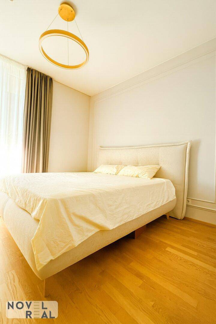 Helles Schlafzimmer mit Doppelbett, Holzboden und großem Fenster für viel Tageslicht.
